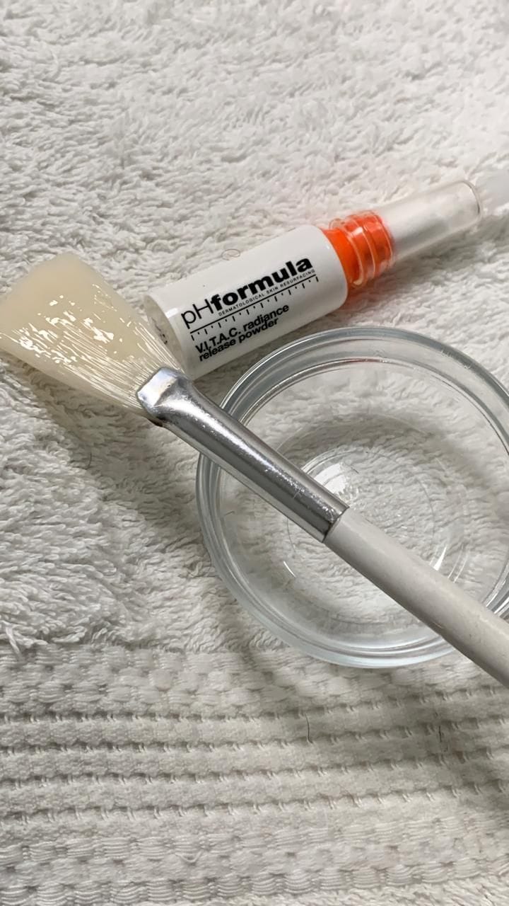 A professional pHformula resurfacing solution and application brush laid out on a clean towel before a peel.